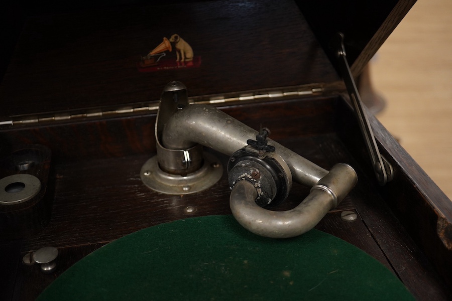 Two gramophone players; an oak cased HMV tabletop gramophone on a similar style mahogany gramophone record stand, height of stand 72.5cm, together with a May-Fair Deluxe Model portable gramophone player. Condition - poor